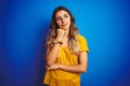 Young beautiful woman wearing yellow t-shirt over blue isolated background with hand on chin thinking about question, pensive Royalty Free Stock Photo