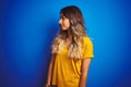 Young beautiful woman wearing yellow t-shirt over blue isolated background looking to side, relax profile pose with natural face Royalty Free Stock Photo