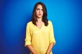 Young beautiful woman wearing yellow t-shirt standing over blue isolated background Relaxed with serious expression on face Royalty Free Stock Photo