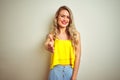 Young beautiful woman wearing yellow t-shirt standing over white isolated background smiling friendly offering handshake as Royalty Free Stock Photo