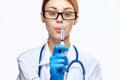 Young beautiful woman on white background with glasses and medical robe holding syringe, doctor, medicine Royalty Free Stock Photo