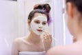 Young beautiful woman with white cosmetic natural healing mask on face