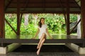 Young and beautiful woman in white dress. Woman posing in exotic Thai bungalow. Resting and traveling concept.