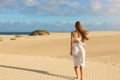 Young beautiful woman with white dress walking on desert dunes at sunset. Girl walking on golden sand on Corralejo Dunas, Royalty Free Stock Photo