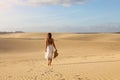 Young beautiful woman with white dress walking in the desert dunes  during sunset. Girl walking on golden sand on Corralejo Dunas Royalty Free Stock Photo