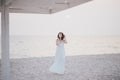 Young beautiful woman in a white dress walking on an empty beach near ocean Royalty Free Stock Photo