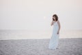 Young beautiful woman in a white dress walking on an empty beach near ocean Royalty Free Stock Photo