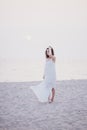 Young beautiful woman in a white dress walking on an empty beach near ocean Royalty Free Stock Photo