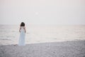 Young beautiful woman in a white dress walking on an empty beach near ocean Royalty Free Stock Photo