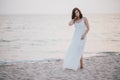 Young beautiful woman in a white dress walking on an empty beach near ocean Royalty Free Stock Photo