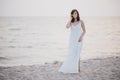 Young beautiful woman in a white dress walking on an empty beach near ocean Royalty Free Stock Photo