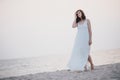 Young beautiful woman in a white dress walking on an empty beach near ocean Royalty Free Stock Photo