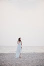 Young beautiful woman in a white dress walking on an empty beach near ocean Royalty Free Stock Photo