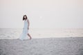 Young beautiful woman in a white dress walking on an empty beach near ocean Royalty Free Stock Photo