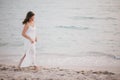 Young beautiful woman in a white dress walking on an empty beach near ocean Royalty Free Stock Photo