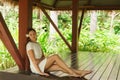 Young and beautiful woman in white dress. Woman posing in exotic Thai bungalow. Resting and traveling concept. Royalty Free Stock Photo