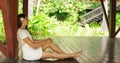Young and beautiful woman in white dress. Woman posing in exotic Thai bungalow. Resting and traveling concept.