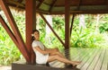 Young and beautiful woman in white dress. Woman posing in exotic Thai bungalow. Resting and traveling concept.