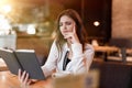 Young beautiful woman in white jacket checking her planner working outside office drinking hot coffee in the trendy cafe looking Royalty Free Stock Photo