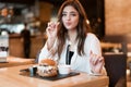 Young beautiful woman in white stylish blouse eating meat burger and fries for lunch in trendy cafe modern businesswoman Royalty Free Stock Photo