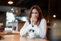 Young beautiful woman in white stylish blouse feeling sick bowing out her nose after hard workday drinking coffee in cafe modern Royalty Free Stock Photo