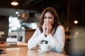 Young beautiful woman in white stylish blouse feeling sick bowing out her nose after hard workday drinking coffee in cafe modern