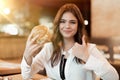 Young beautiful woman in white stylish blouse holding rasty fresh meat burger during lunch in trendy cafe showing like eating Royalty Free Stock Photo