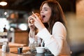 Young beautiful woman in white stylish blouse looks hungry biting fresh meat burger during lunch in trendy cafe eating outside Royalty Free Stock Photo