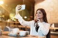 Young beautiful woman in white stylish blouse looks nice while taking selfie before having meat burger with fries for lunch in Royalty Free Stock Photo