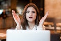 Young beautiful woman in white stylish jacket working in her laptop feeling stressed after hard workday sitting in trendy cafe Royalty Free Stock Photo