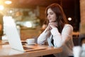 Young beautiful woman in white stylish jacket working in her laptop outside office during coffee break in cafe modern Royalty Free Stock Photo