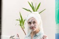 A young beautiful woman with a white towel on her head in the bathroom applied makeup remover to her face against the background o Royalty Free Stock Photo