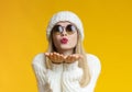 Young beautiful woman in winter hat and sunglasses blowing kiss Royalty Free Stock Photo