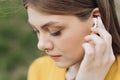 Young beautiful woman with wireless earphones on her ears. Close up of female ear with wireless earphone inside Royalty Free Stock Photo