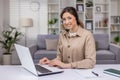 Young beautiful woman working from home remotely, businesswoman smiling and looking at camera, using headset phone and Royalty Free Stock Photo