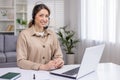 Young beautiful woman working from home remotely, businesswoman smiling and looking at camera, using headset phone and Royalty Free Stock Photo