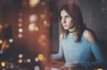 Young beautiful woman working on modern loft office at night. Girl using contemporary desktop computer, blurred