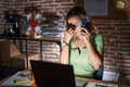 Young beautiful woman working at the office at night speaking on the phone tired rubbing nose and eyes feeling fatigue and Royalty Free Stock Photo