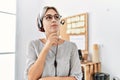 Young beautiful woman working at the office wearing operator headset serious face thinking about question with hand on chin, Royalty Free Stock Photo