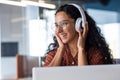 Young beautiful woman working in the office at the workplace, close-up hispanic woman in headphones singing along and