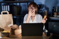 Young beautiful woman working using computer laptop and eating delivery food bored yawning tired covering mouth with hand Royalty Free Stock Photo