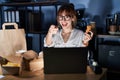 Young beautiful woman working using computer laptop and eating delivery food pointing fingers to camera with happy and funny face Royalty Free Stock Photo