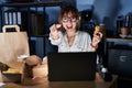 Young beautiful woman working using computer laptop and eating delivery food pointing to you and the camera with fingers, smiling Royalty Free Stock Photo