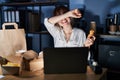 Young beautiful woman working using computer laptop and eating delivery food smiling cheerful playing peek a boo with hands Royalty Free Stock Photo