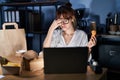 Young beautiful woman working using computer laptop and eating delivery food tired rubbing nose and eyes feeling fatigue and Royalty Free Stock Photo