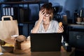 Young beautiful woman working using computer laptop and eating delivery food yawning tired covering half face, eye and mouth with Royalty Free Stock Photo