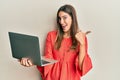 Young beautiful woman working using computer laptop pointing thumb up to the side smiling happy with open mouth Royalty Free Stock Photo