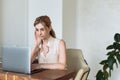 Young beautiful woman works for a computer from a home with a laptop on a desk as a freelancer Royalty Free Stock Photo