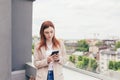 Young beautiful woman writes on the phone, standing on the balcony of the office center Royalty Free Stock Photo