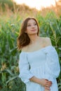 Young beautiful woman 26 years old in white simple dress in summer field. Green corn. Summer. Rustic style Royalty Free Stock Photo